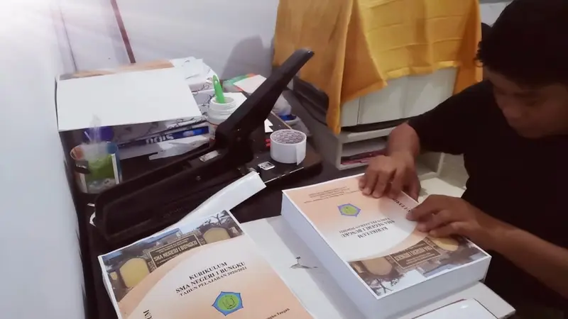 orang sedang melakukan stapler hard cover